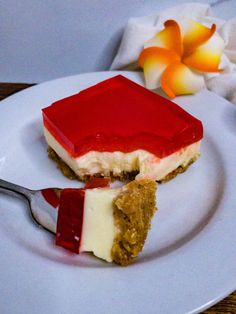 a piece of cheesecake on a plate with a fork and flower in the background