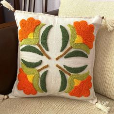 a decorative pillow on a couch with tassels and flowers in the center,