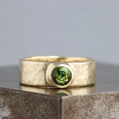 a gold ring with a green stone in the center