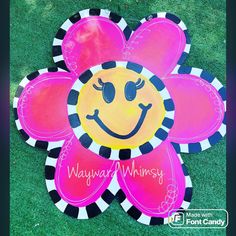 a pink and black flower with a smiley face painted on it's center piece