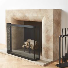 a fireplace with a fire in it next to a black iron fence and wooden logs