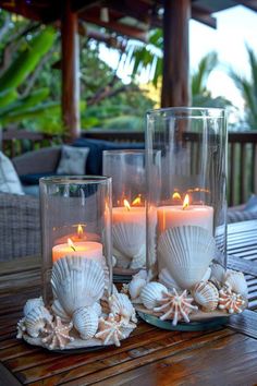 three candles are sitting on a table with seashells