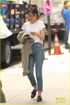 a woman walking down the street while looking at her cell phone