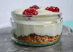 a dessert in a glass jar with whipped cream and raspberries on the top