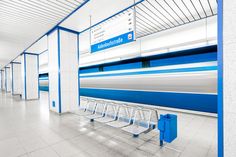 an empty blue and white train station with benches