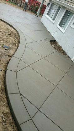 an outdoor patio with concrete walkways and landscaping equipment in the foreground, next to a house