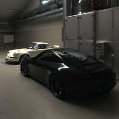 two porsches are parked in a large garage