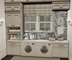 a washer and dryer in a room with white cupboards, drawers, and wallpaper