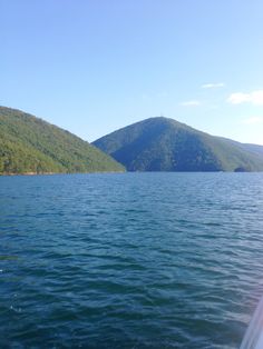 there is a boat that is going down the water and mountains in the back ground