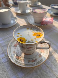 White teacup on saucer with orange accent flowers and white candle on the inside of the tea cup. Decorated with yellow flowers and greenery on top. Teacup Candles, Candle Craft, Cadeau Diy