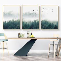 three paintings hang on the wall above a dining room table with two chairs and a bar stool