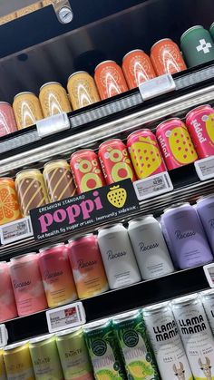 many different flavored beverages are on display in a store shelf with the name poppi