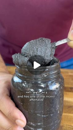 a person is holding a spoon in a jar with some sort of substance on it