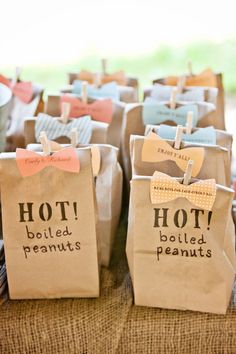 small bags with bow ties on them are sitting on a table in front of other paper bags