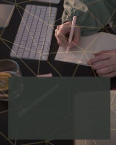 a person sitting at a desk writing on a piece of paper with a flower in front of them