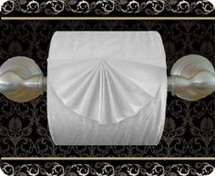 a white toilet paper roll sitting on top of a black and gold wall mounted tissue dispenser