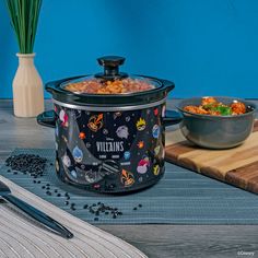 a crock pot filled with food sitting on top of a table next to a bowl of beans