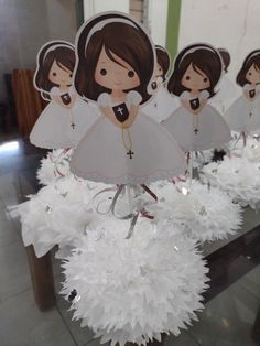 some paper angel decorations are hanging from a table with white pom - poms