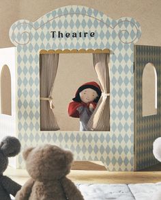 two teddy bears sitting next to each other in front of a puppet house with the word theatre on it