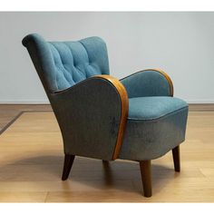 a blue chair sitting on top of a hard wood floor next to a white wall