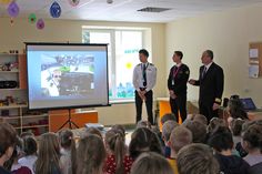 three men standing in front of a class room full of people with a projector screen