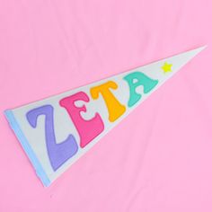 a felt pennant with the word zest written in multicolored letters on it