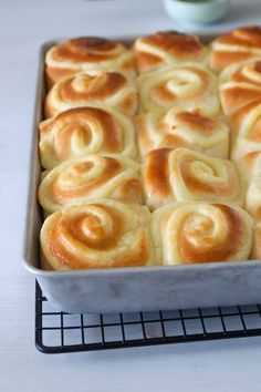 a pan filled with rolls sitting on top of a metal rack next to a white counter