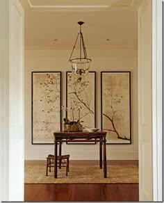 a dining room table and chairs with artwork on the wall behind them in an open doorway