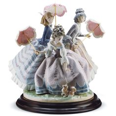 a figurine of three ladies with parasols and a cat on a pedestal