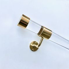 a gold toilet roll holder on a white wall next to a glass tube with the lid open