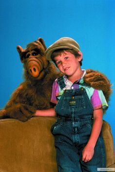 a young boy sitting on top of a couch next to a large stuffed animal bear