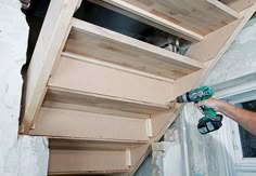 a man using a power drill to attach shelves