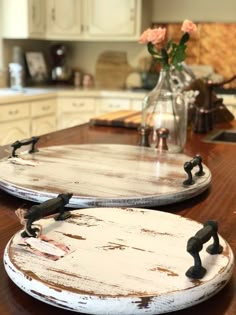 two wooden trays sitting on top of a kitchen counter next to a vase with flowers