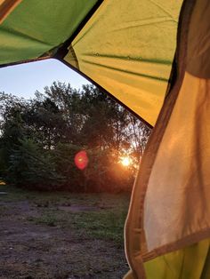 the sun is setting behind an open tent