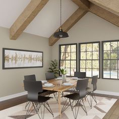 a dining room table and chairs in front of large windows with wood beams on the ceiling