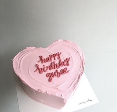 a heart shaped birthday cake with pink frosting