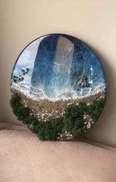 a round plate with grass and rocks on the bottom is sitting on a couch in front of a wall