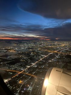 the view from an airplane window at night with lights on and city lights in the distance