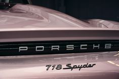 porsche emblem on the back of a pink sports car