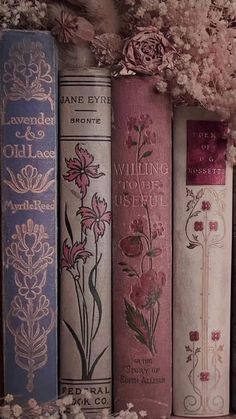 there are many books lined up on the shelf with flowers in them and one is pink