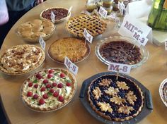 a table topped with pies and pie plates covered in pie toppings on top of wooden tables