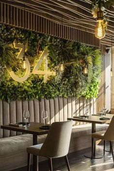 the restaurant is decorated with greenery on the wall and wooden tables in front of it