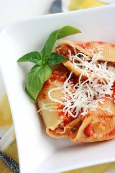 a white plate topped with pasta covered in sauce and cheese