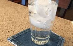 a glass with ice in it sitting on top of a table