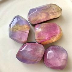 five amethyst stones sitting on top of a white plate with yellow and pink accents