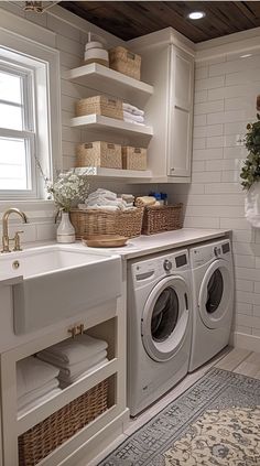 a washer and dryer in a white laundry room with open shelving on the wall