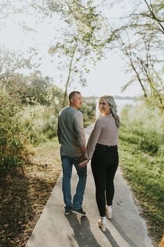 a man and woman walking down a sidewalk holding hands