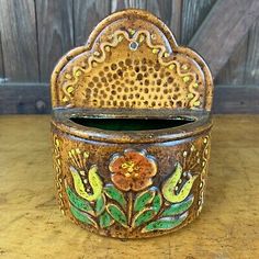 an old tin can with flowers painted on it