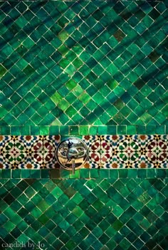 a green tiled wall with a mirror in the middle