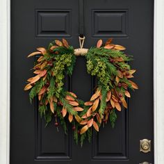 a wreath is hanging on the front door with green and red foliages around it